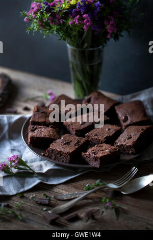 Dark chocolate coconut oil brownies on a plate on rustic wooden table. Stock Photo