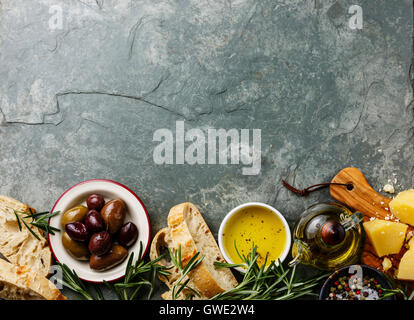 Italian food ingredients background with Sliced bread Ciabatta, parmesan, olive oil, olives and rosemary on gray stone slate