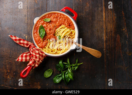 Spaghetti Bolognese with tomato sauce and basil in iron pan on wooden background Stock Photo