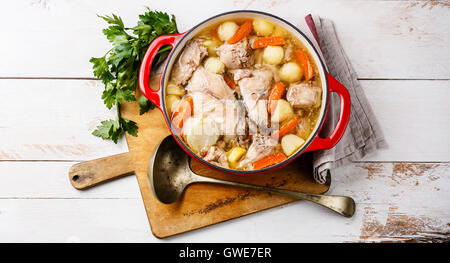 Stewed rabbit with potatoes and carrot in cast iron pot on rustic wooden table background Stock Photo