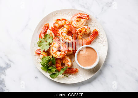 Roasted Prawns on white plate with cocktail sauce on white marble background Stock Photo