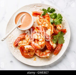 Roasted Prawns on white plate with cocktail sauce on white marble background Stock Photo