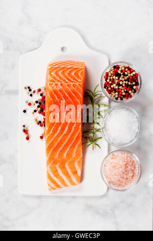 Delicious portion of fresh salmon fillet with aromatic herbs and spices - healthy food, diet or cooking concept. Top view. Stock Photo