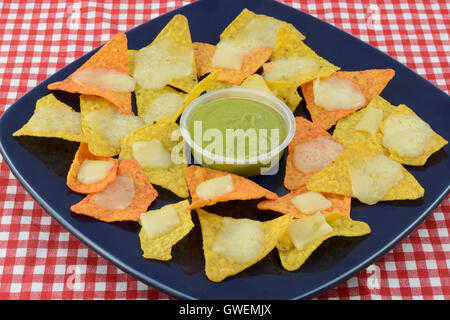 Nachos melted cheese and with guacamole dip on blue plate Stock Photo