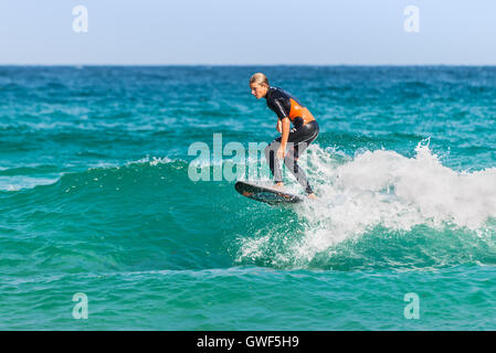A man rides his surfboard towards the shore.