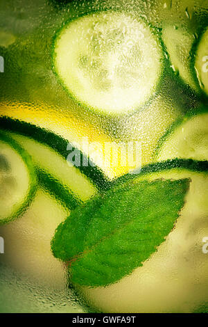 Infused water with cucumber, lemon, lime and mint on blue background Stock Photo