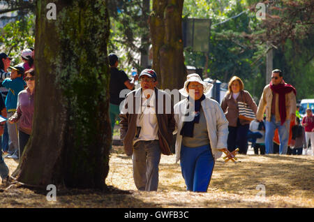 QUITO, ECUADOR - JULY 7, 2015: Two adults with sun protection walking through a park to arrive to pope Francisco mass Stock Photo