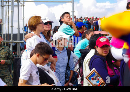 QUITO, ECUADOR - JULY 7, 2015: Adults, woman and men, paying attention to pope Francisco mass, sunny day Stock Photo