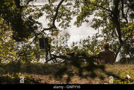 Berlin, Germany. 13th Sep, 2016. A man sitting on the banks of Tegler See lake in Berlin, Germany, 13 September 2016. PHOTO: PAUL ZINKEN/DPA/Alamy Live News Stock Photo
