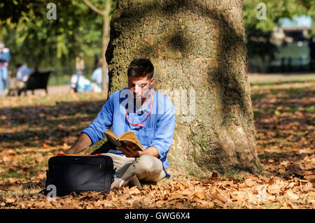 Young man sitting and reading book in a park