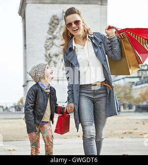 Stylish autumn in Paris. Full length portrait of happy modern mother and daughter with shopping bags in Paris, France walking Stock Photo