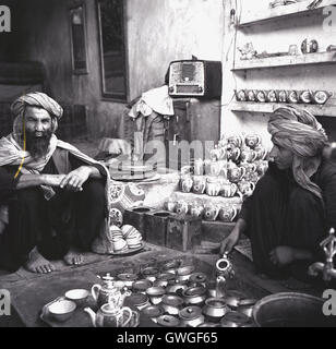1950s, historical, two local afghans sitting with their tin goods, Kabul, Afghanistan. Stock Photo