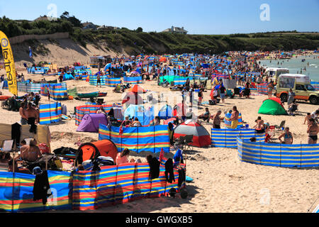 A beach crowded with holidaymakers and windbreaks at Harlyn Bay, North Cornwall. Stock Photo