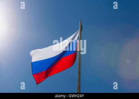 National flag of Russia on a flagpole in front of blue sky Stock Photo