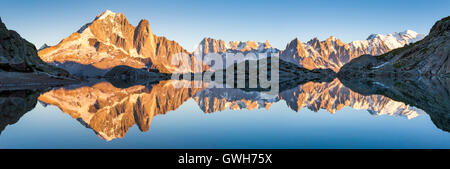 Beautiful panorama of Alps mountain range with sunset lights and reflection in an altitude lake near Chamonix, France Stock Photo