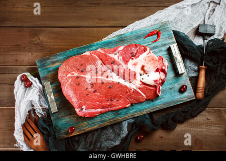 Fresh beef veal meat on rustic wooden table with kitchen utensils Stock Photo