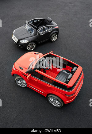 Kids electric cars standing empty on a playground with another kids electric play vehicle Stock Photo