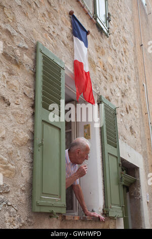 Elderly Frenchman smoking leaning out window Stock Photo