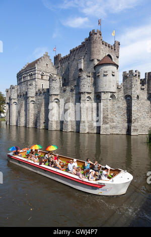 tourist boat full of colorful people on river near Gravenstein Castle in belgian medieval city centre of Ghent Stock Photo