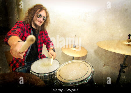 Drums conceptual image. Rock drummer holding drumsticks and playing on drums. Retro vintage grunge picture. Stock Photo