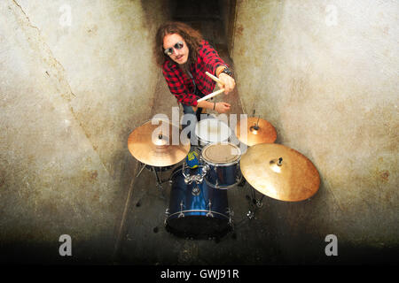 Drums conceptual image. Rock drummer holding drumsticks and playing on drums. Retro vintage grunge picture. Stock Photo