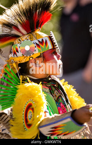 A young Native American dancer from the Arapahoe people dressed in traditional costume waits to perform at the Indian Village during Cheyenne Frontier Days July 25, 2015 in Cheyenne, Wyoming. Frontier Days celebrates the cowboy traditions of the west with a rodeo, parade and fair. Stock Photo