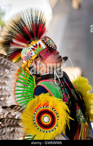 A young Native American dancer from the Arapahoe people dressed in traditional costume waits to perform at the Indian Village during Cheyenne Frontier Days July 25, 2015 in Cheyenne, Wyoming. Frontier Days celebrates the cowboy traditions of the west with a rodeo, parade and fair. Stock Photo