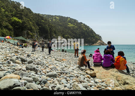 Korean tourists at a pebble rock beach at the Taejongdae Resort Park in Busan, South Korea. Stock Photo