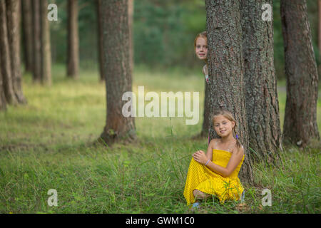 Two little girls pose for the camera among the pines in the Park. Stock Photo