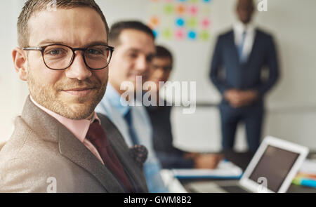Group of four multi-cultural executives in a meeting at their office in front of laptop and white board Stock Photo