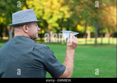 man holding a paper plane in the hand on meadow Stock Photo