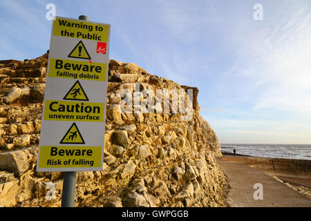 Warning signs next to chalk cliffs on promenade, Seaford, East Sussex, England Stock Photo