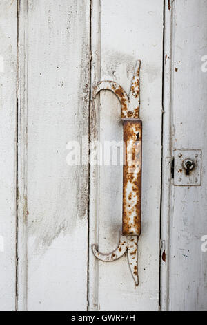 Rusty metal handle on antique painted white wooden door in Toulouse, France, closeup. Stock Photo