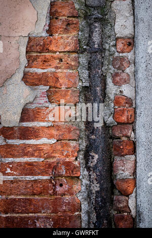 Antique wall with red old bricks, rusty metal and layers of plaster in Toulouse, France, closeup. Stock Photo