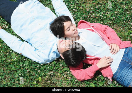 Young Japanese couple laying on grass Stock Photo