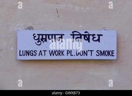 Humorous, originally expressed No Smoking sign on wall written in English and Hindi as a polite request Stock Photo