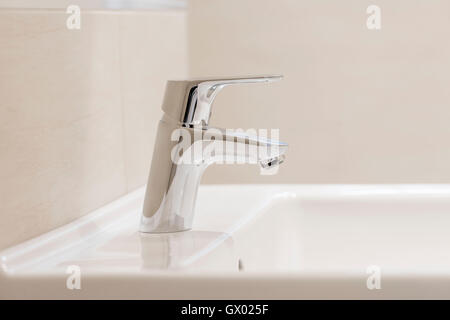 Polished chrome mixer tap on white washbasin in bathroom Stock Photo