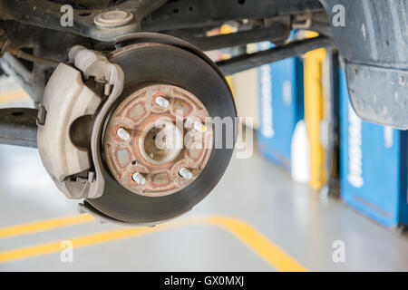Front disc brake on car in process of new tire replacement Stock Photo