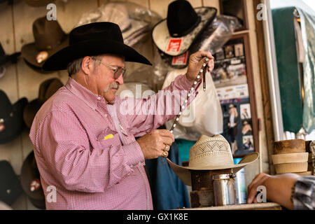 A hat shaper works on customizing a cowboy hat for a customer at Cheyenne Frontier Days July 25, 2015 in Cheyenne, Wyoming. Frontier Days celebrates the cowboy traditions of the west with a rodeo, parade and fair. Stock Photo