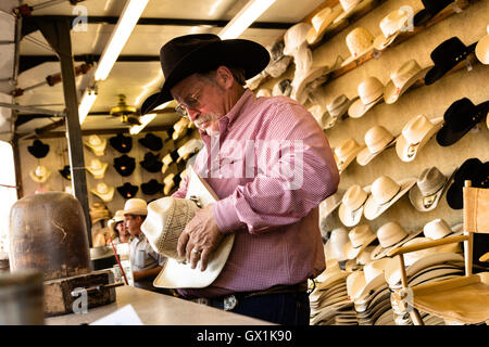 A hat shaper works on customizing a cowboy hat for a customer at Cheyenne Frontier Days July 25, 2015 in Cheyenne, Wyoming. Frontier Days celebrates the cowboy traditions of the west with a rodeo, parade and fair. Stock Photo