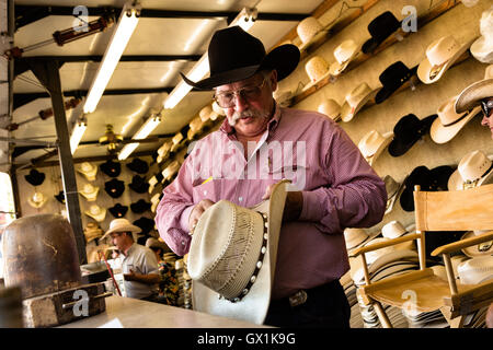 A hat shaper works on customizing a cowboy hat for a customer at Cheyenne Frontier Days July 25, 2015 in Cheyenne, Wyoming. Frontier Days celebrates the cowboy traditions of the west with a rodeo, parade and fair. Stock Photo