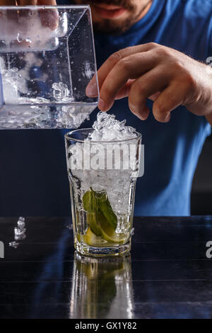 Pouring fresh mojito cocktail in glasses isolated on black background ...