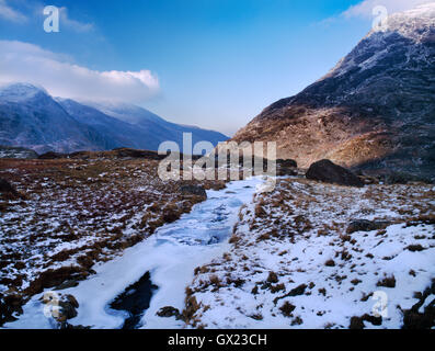 Partly frozen stream flowing down from Llyn Bochlwyd to Llyn Ogwen in Snowdonia: view NNW to Yr Ole Wen (R) & Nant Ffrancon (L). Stock Photo