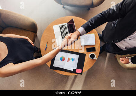 Top view of young business partners shaking hands over deal at office. Focus on handshake. Stock Photo