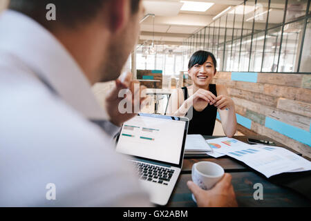 Shot of two business colleagues discussing work in office. Smiling young asian woman meeting with office manager. Stock Photo