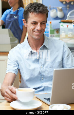 Man In Coffee Shop Using Laptop Computer Stock Photo