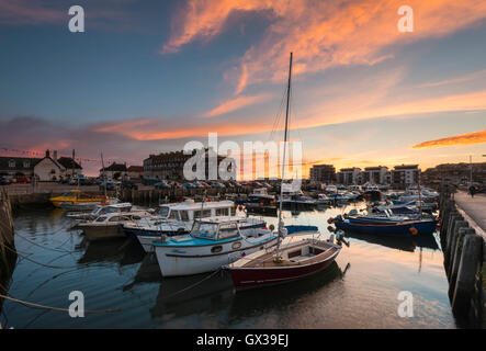 West Bay, Dorset, UK - 14th September 2016. UK Weather.  A glorious sunset illuminating the clouds above West Bay Harbour in Dorset, UK.  West Bay is one of the locations for the hit ITV series Broadchurch.  Picture: Graham Hunt/Alamy Live News