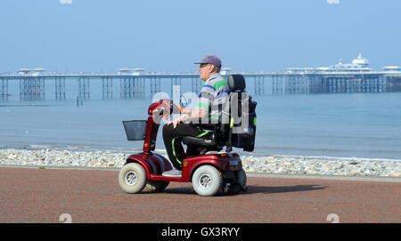 MAN ON MOBILITY SCOOTER ON THE PROMENADE AT LLANDUDNO NORTH WALES RE DISABILITY CARE ELDERLY RETIREMENT PENSIONERS SEASIDE UK Stock Photo