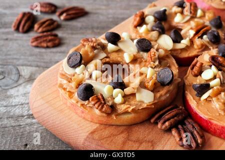 Autumn apple rounds with peanut butter, chocolate chips and nuts on a wooden paddle board Stock Photo