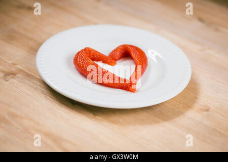 Salmon caviar in the shape of  heart  at plate a on wooden table Stock Photo